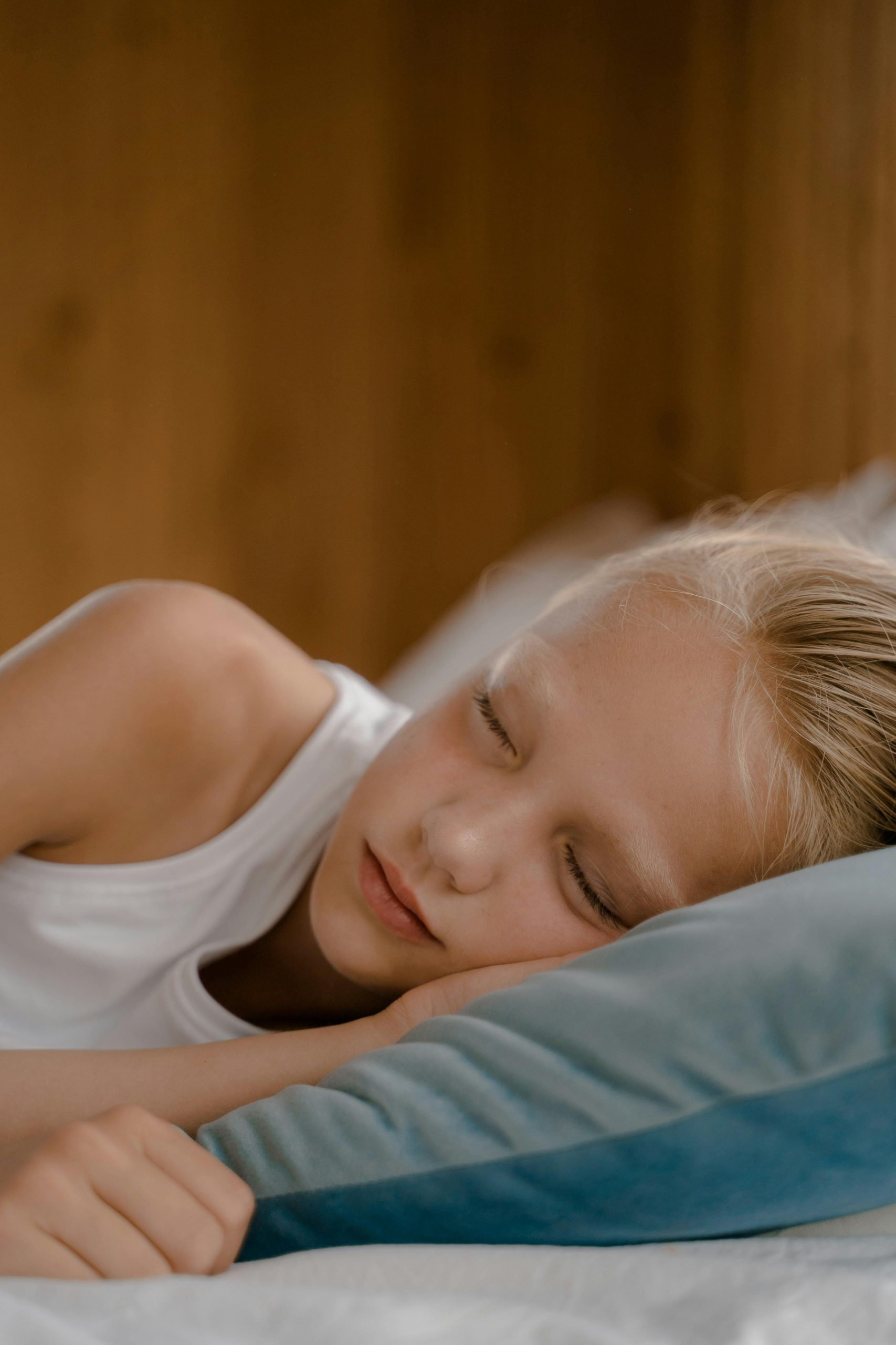 Une jeune fille endormie sur un coussin, avec les yeux fermés et une expression tranquille.
